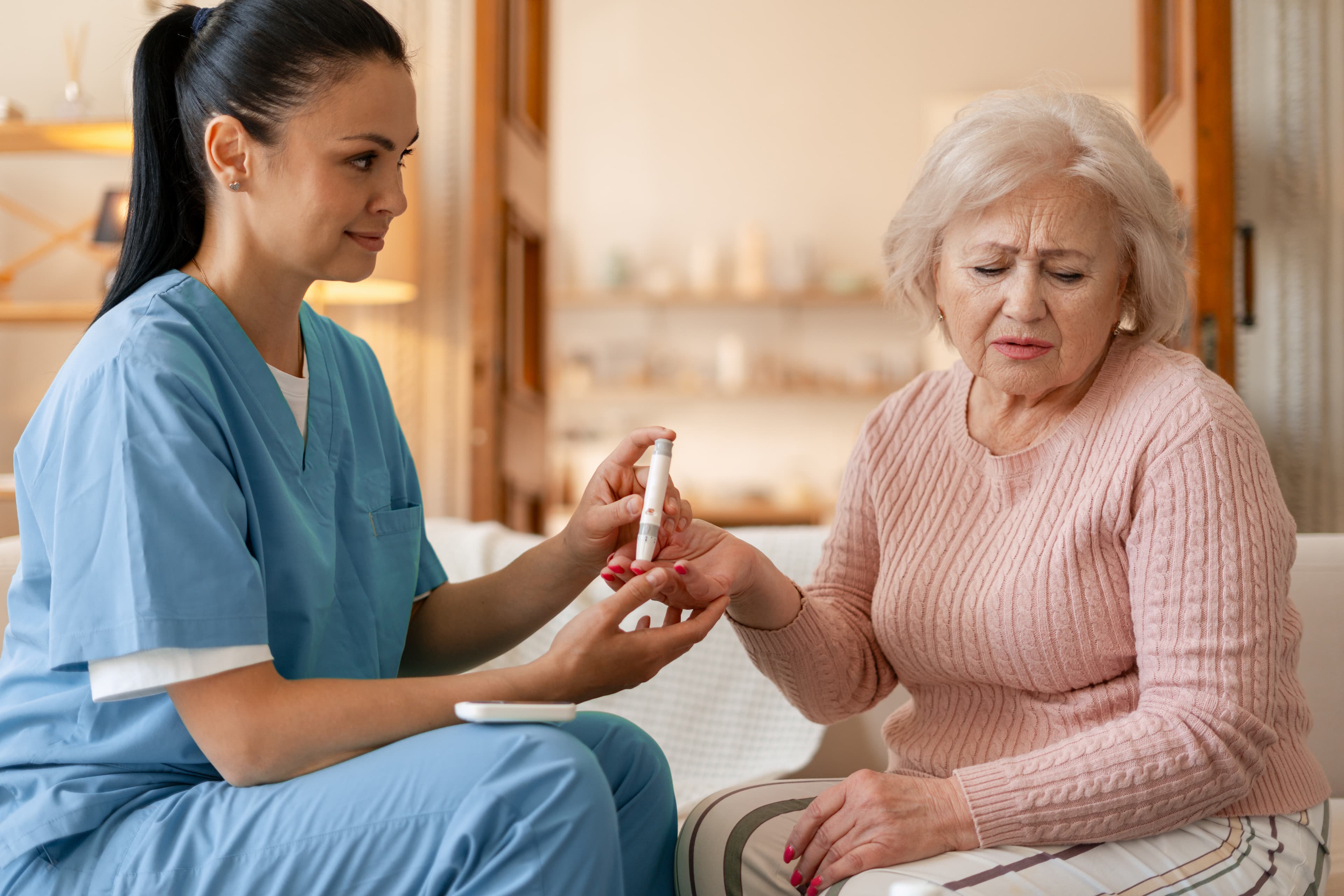 A calm nurse sitting with an older woman at home, supporting her patiently