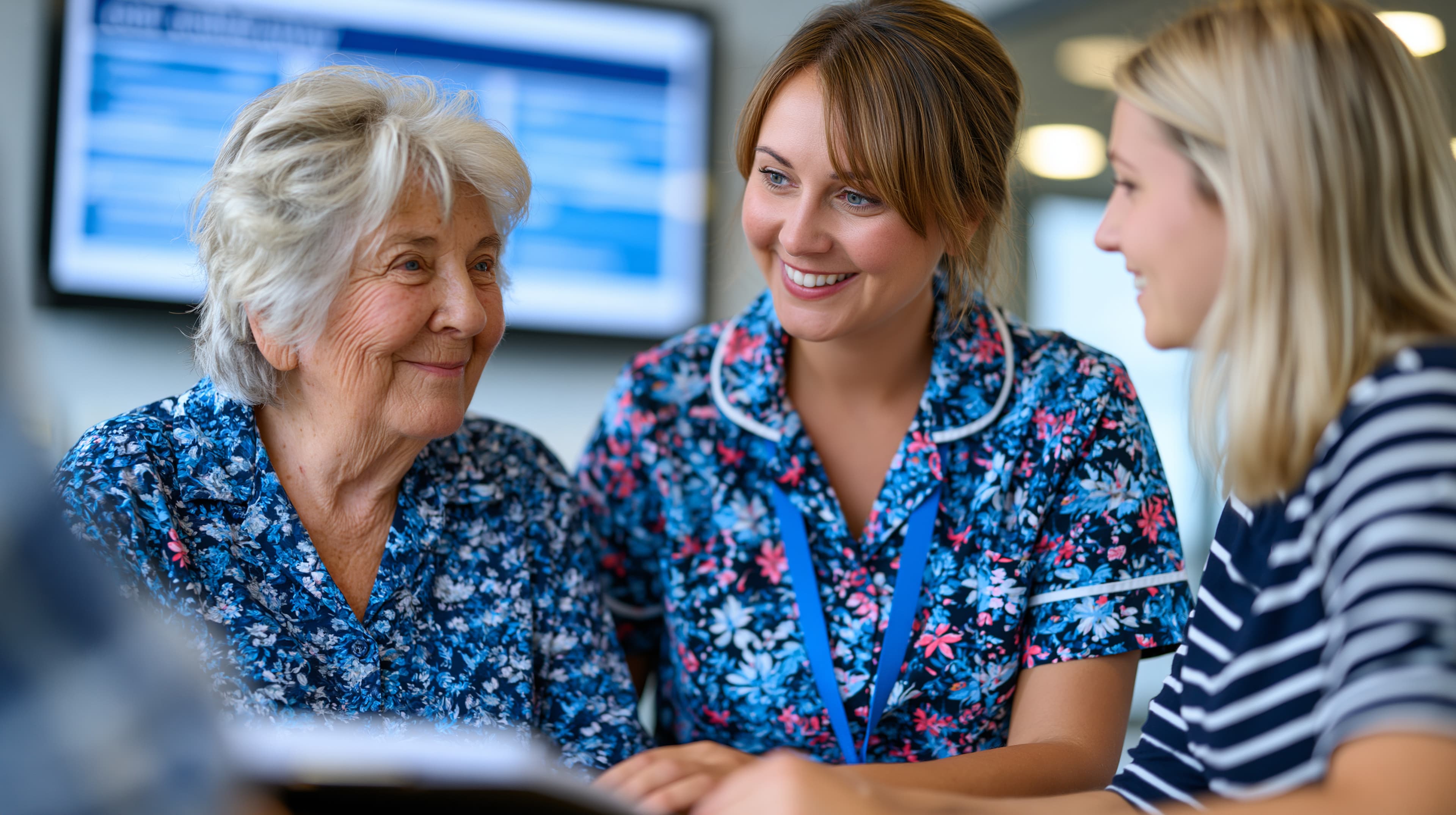 An older woman, a nurse and a younger family member talking together at a table