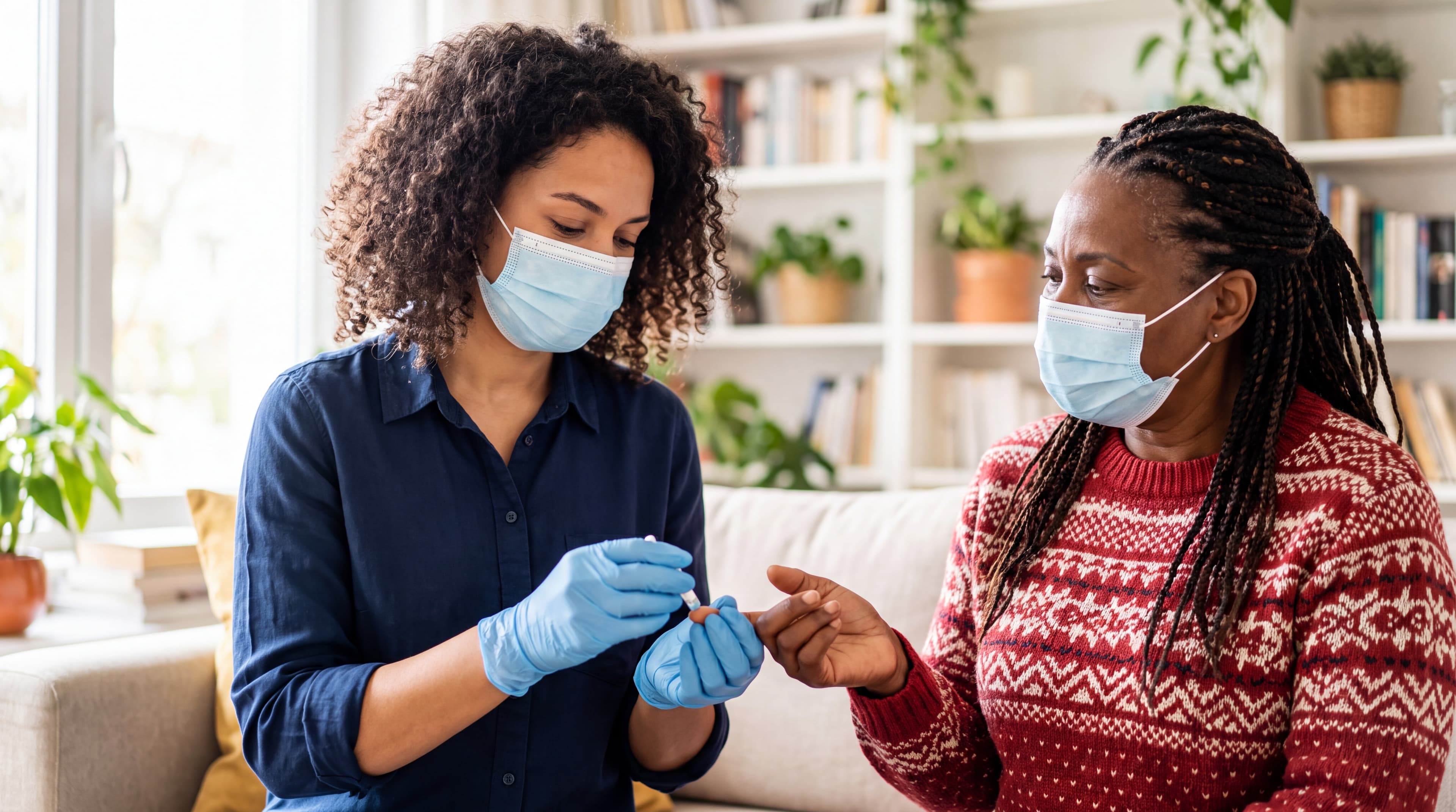 A masked professional in gloves helping a woman check her blood sugar with a finger-stick at home