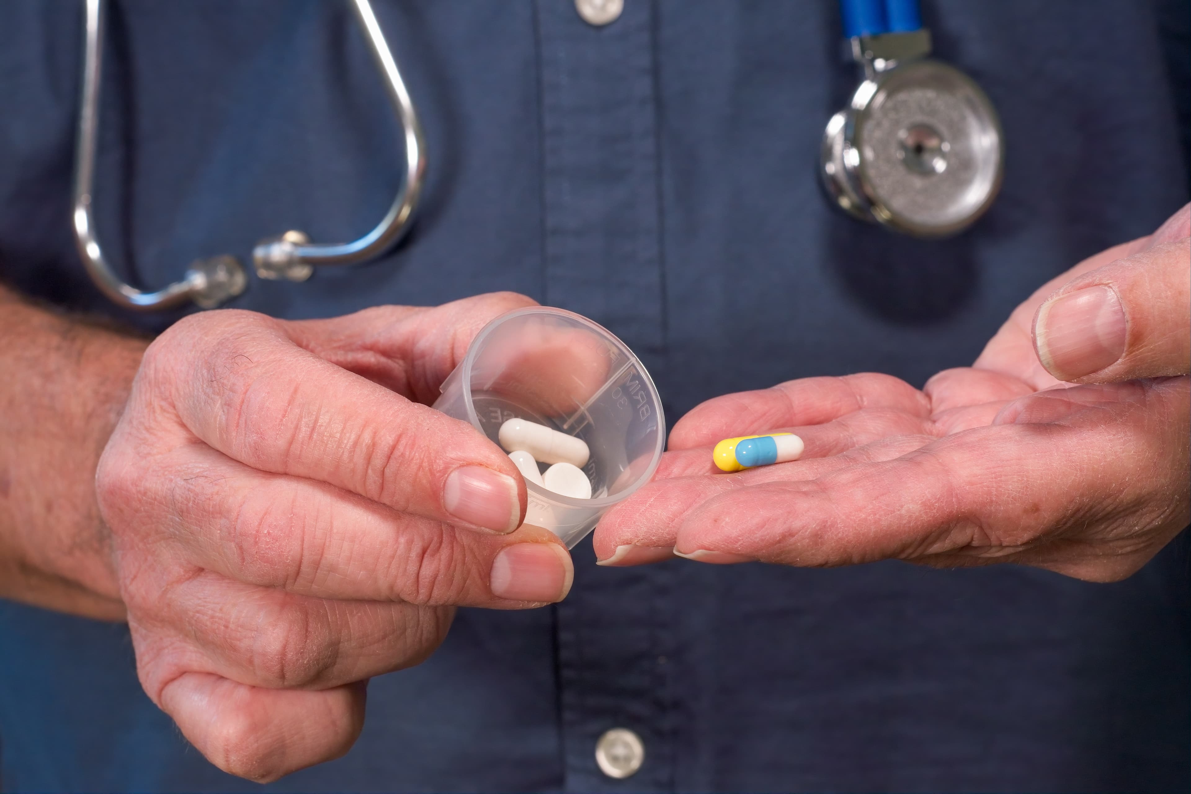 A clinician pouring medications from a cup into their hand